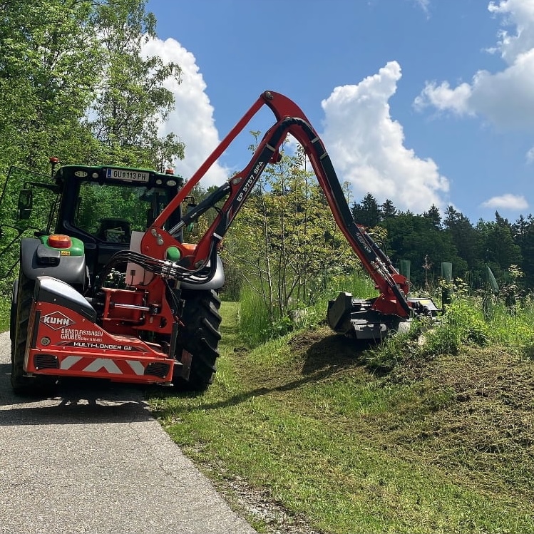 Das Bild zeigt einen Traktor beim Mähen einer Böschung.